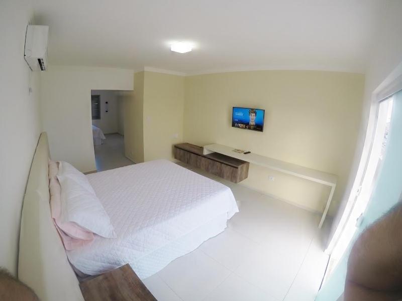 1 dormitorio con 1 cama blanca y TV en Pousada Solar de Penha, en Penha