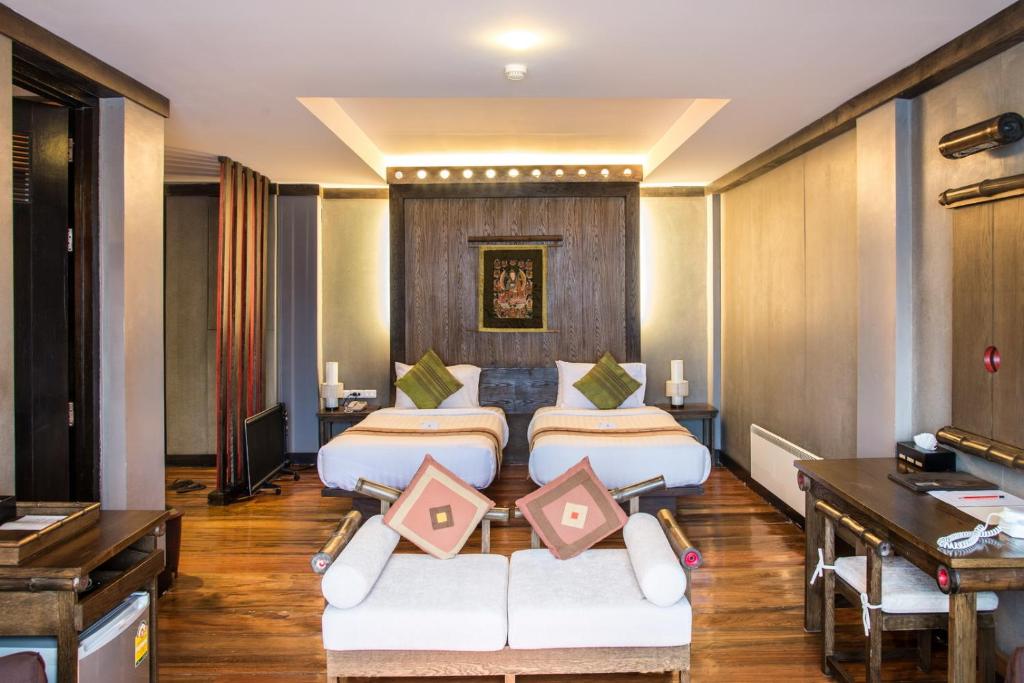 a hotel room with three beds and a desk at Haven Resort Paro in Paro