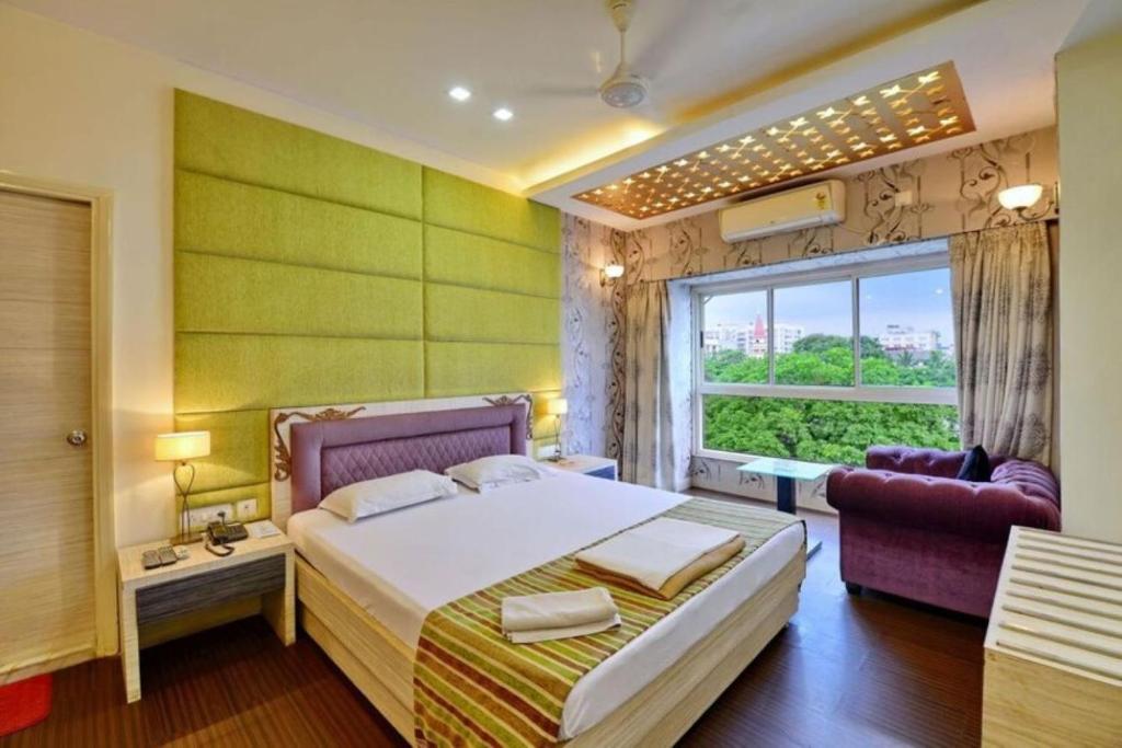 a bedroom with a large bed and a window at Hotel Rushabh Home in Kolkata