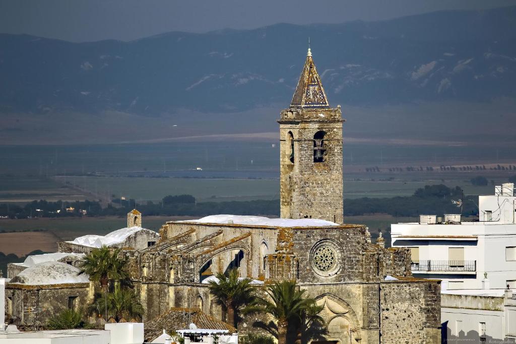 un antiguo edificio con una torre de reloj en una ciudad en Apartamentos Casamonteymar, en Vejer de la Frontera