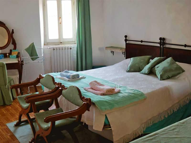 a bedroom with a large bed with two chairs at Casa alla Rocca in Petritoli