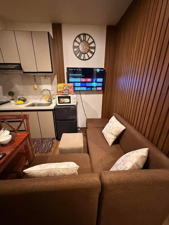 a living room with a couch and a kitchen with a clock at Bunker in Baguio