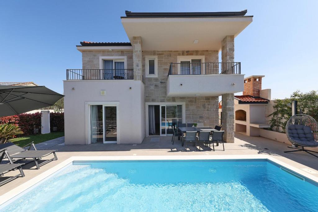 a villa with a swimming pool in front of a house at Casa Coral in Zadar