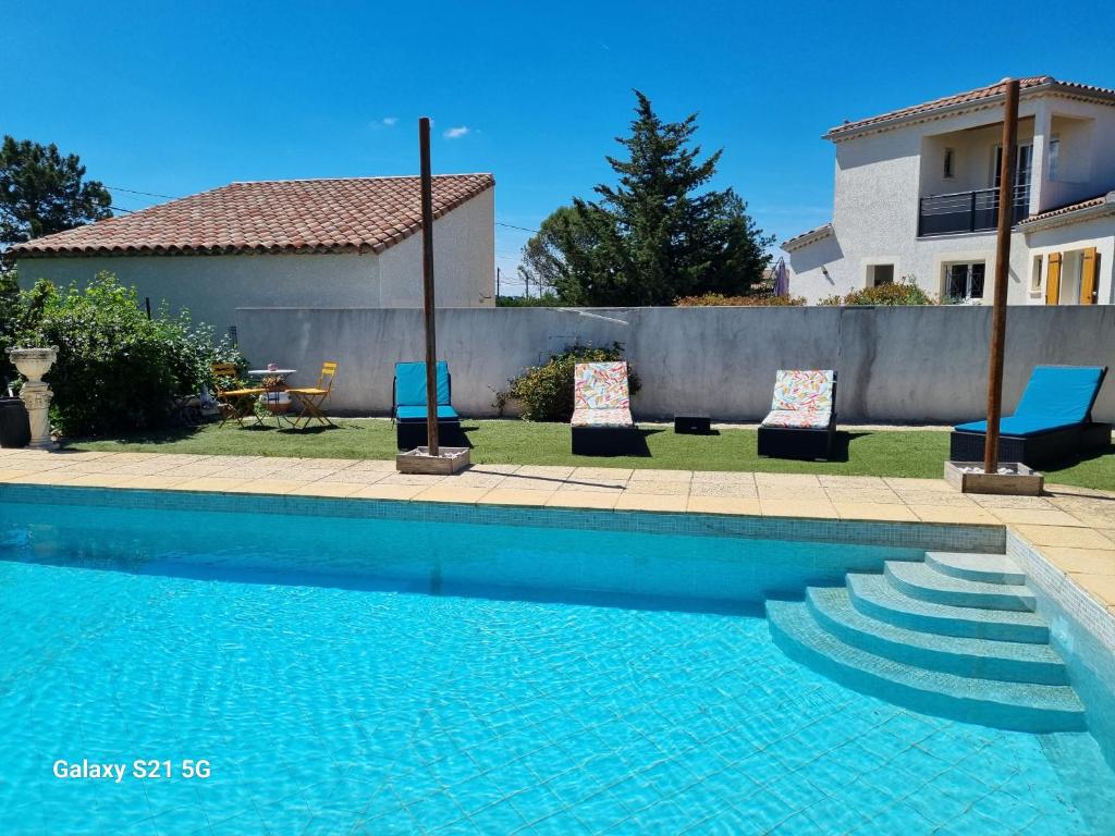 a swimming pool with two chairs and a house at L'escapade des Cévennes in Rousson