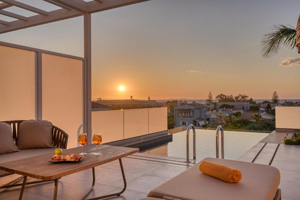ein Wohnzimmer mit einem Tisch und Weingläsern auf einem Balkon in der Unterkunft Thimios Suites Adults Only in Acharavi