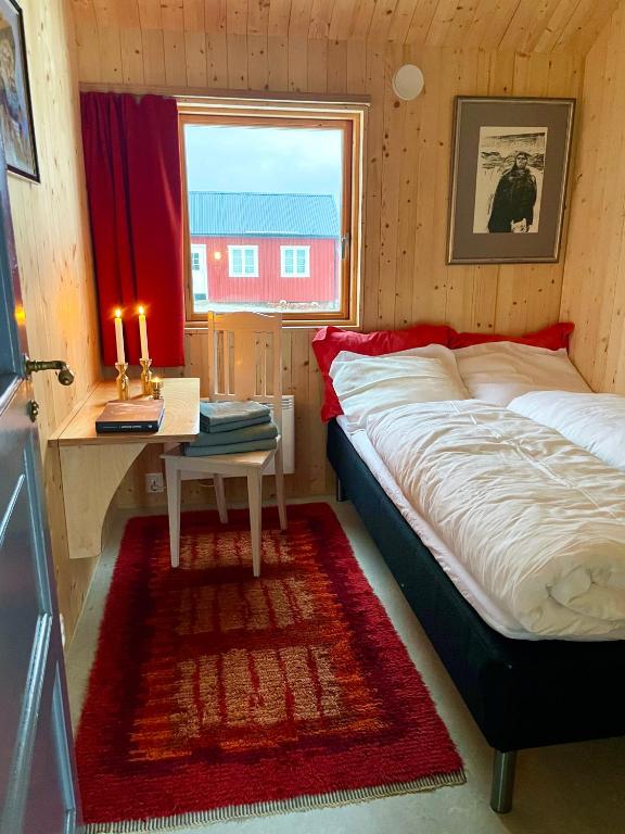 ein Schlafzimmer mit einem Bett, einem Tisch und einem Fenster in der Unterkunft Villa Lofoten - Edvardbua in Kvalnes