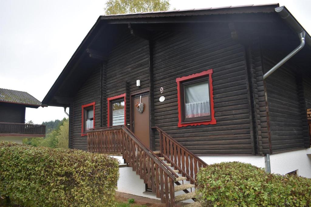 a black house with red windows and a staircase at Ferienwohnung Angela in Thalfang
