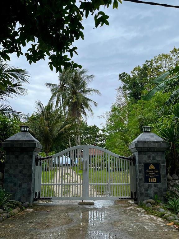 a white gate in a driveway with trees at Damar Tree Resort in Krui