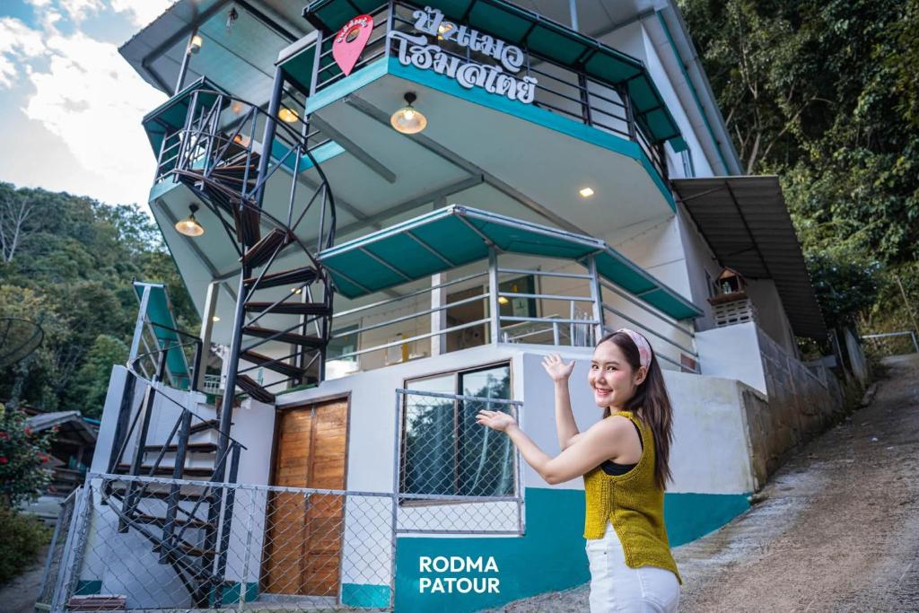 a woman standing in front of a house at ป้าแมว โฮมสเตย์ in Ban Pok Nai