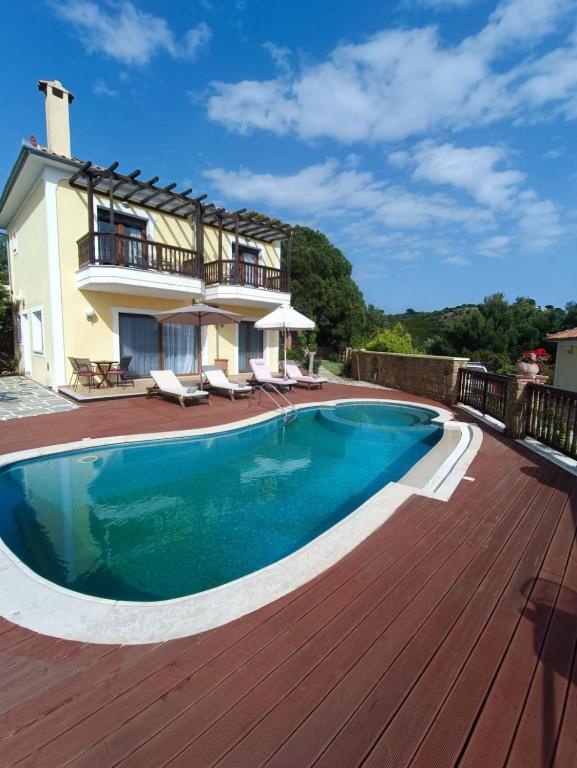 a swimming pool on a wooden deck next to a house at Cave Luxury Villas Skiathos in Troulos