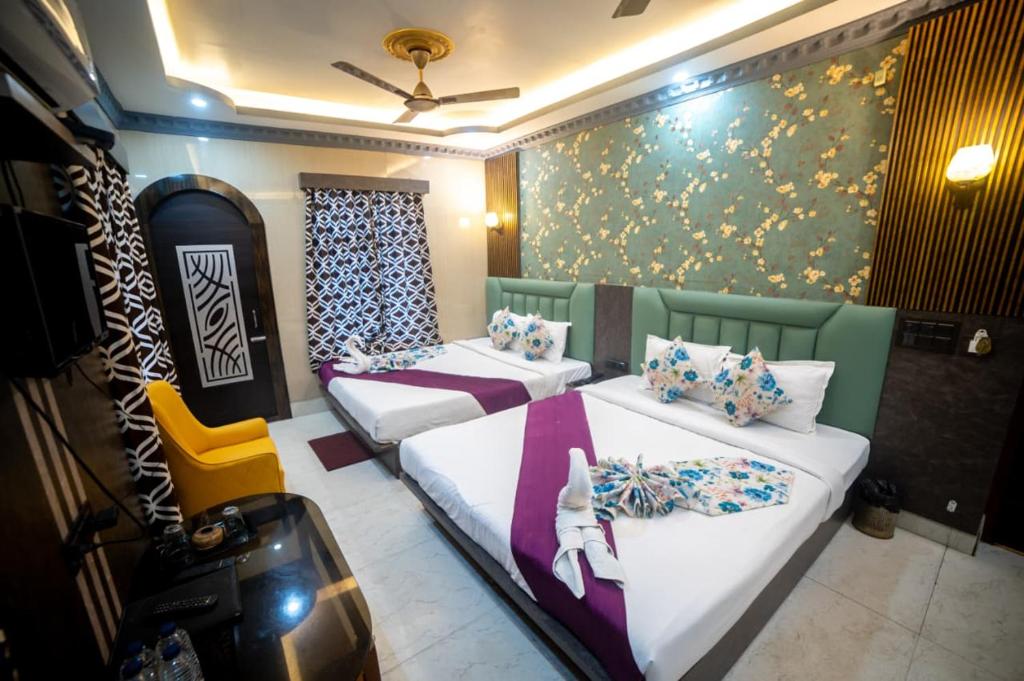 a room with two beds and a wall with flowers at Hotel Priyadarshini in Digha