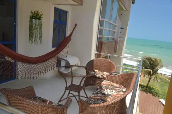balcón con mesa, sillas y vistas al océano en Costeira Praia Apartamento, en Natal