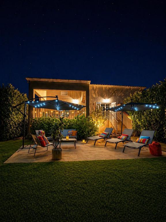 a patio with chairs and umbrellas at night at Campo Vecchio Kamerops et piscine in Ghisonaccia
