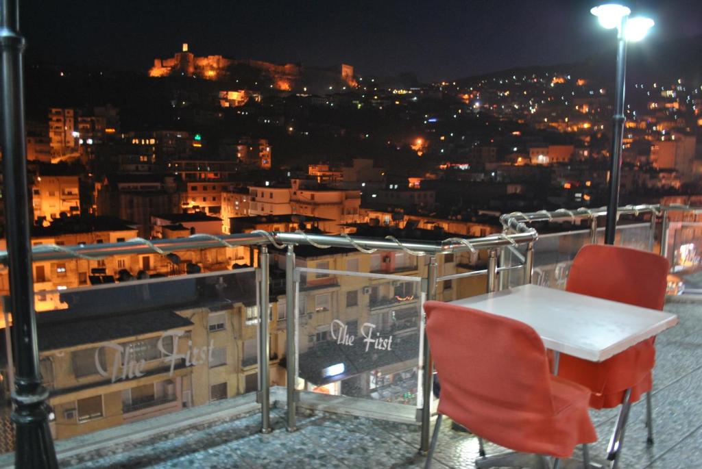 una mesa y sillas en un balcón por la noche en Hotel The First, en Gjirokastra