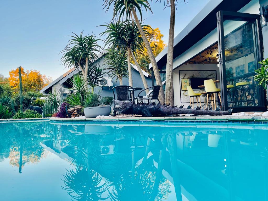 a house with palm trees and a swimming pool at 24 On Basil Boutique Luxury hotel in Johannesburg