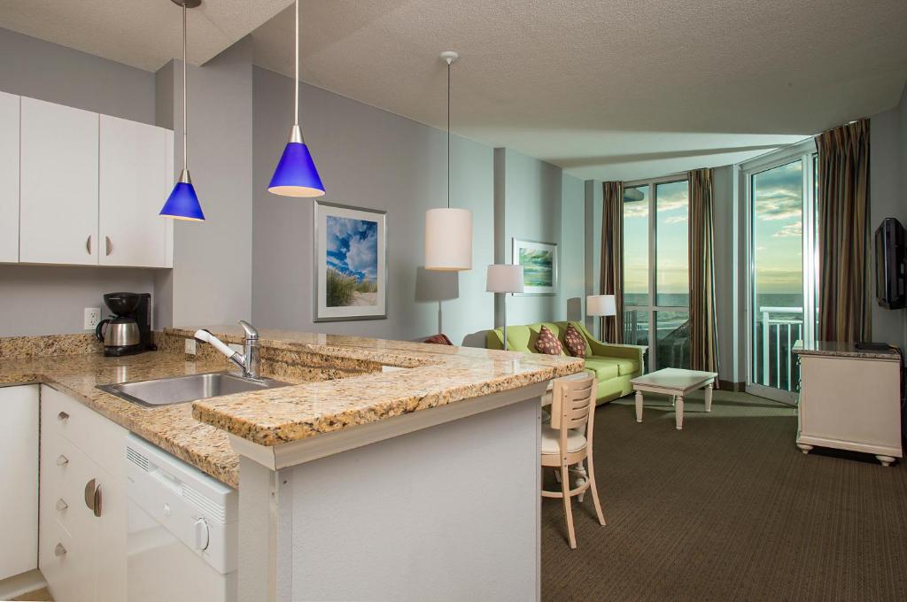 a kitchen with a sink and a living room at Avista Resort in Myrtle Beach