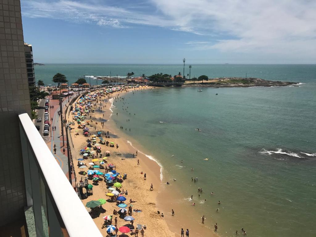 uma praia com um monte de guarda-sóis e pessoas nela em Apartamento Guarapari com simpatia em Guarapari