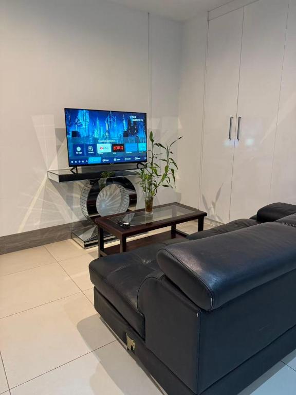a living room with a black couch and a tv at island payless private room in Nadi
