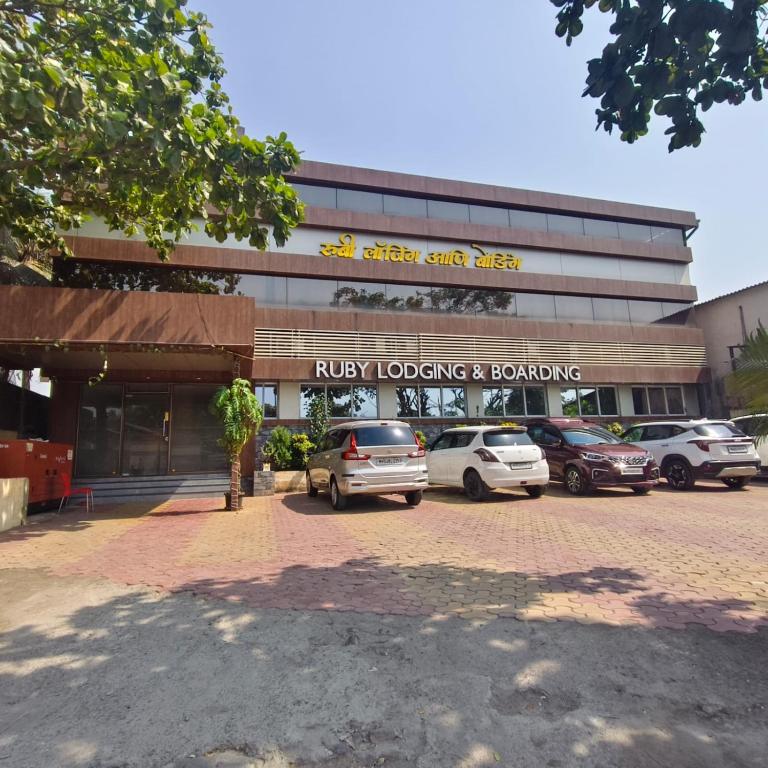 a building with cars parked in a parking lot at Ruby Lodging And Boarding in Mangrul