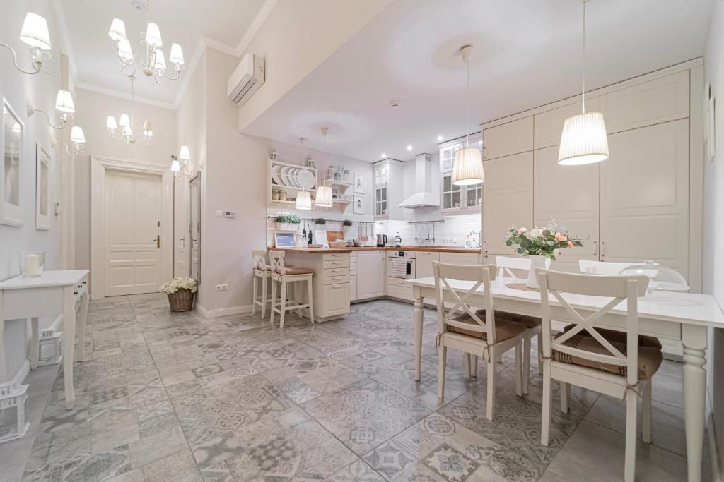 a white kitchen with a dining table and chairs at Serenity Boutique Budapest in Budapest