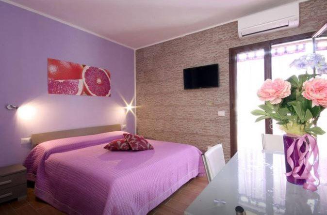 ein Schlafzimmer mit einem rosa Bett und einer Vase aus rosa Rosen in der Unterkunft Lemon&Orange in Castellammare del Golfo