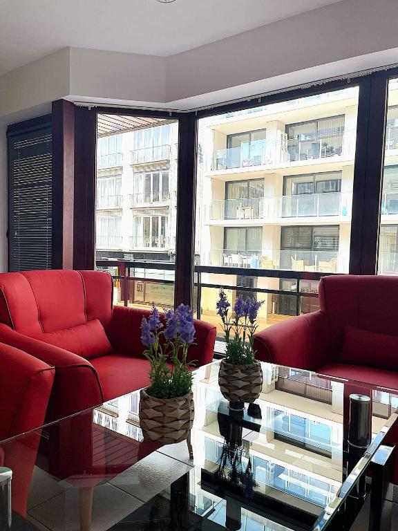 a living room with red couches and a glass table at The Waves in Ostend