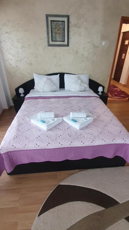 a bed with a purple comforter with two dishes on it at Apartament RHC in Târgu Ocna