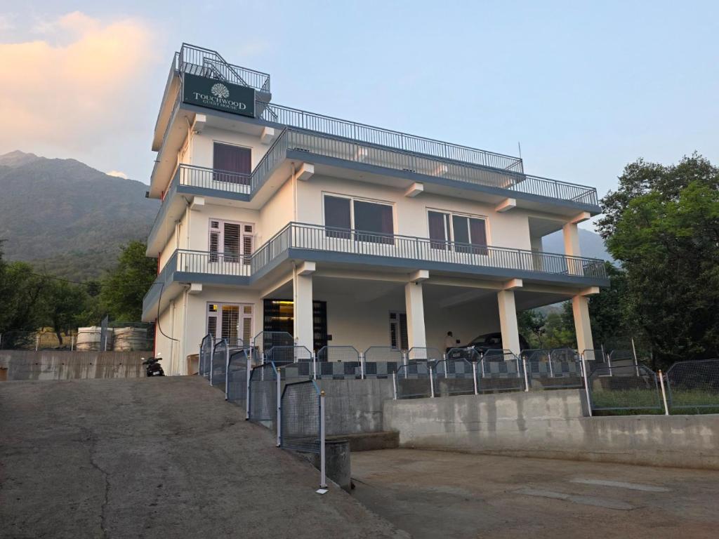 a white building with a balcony on top of it at Touch wood guest house in Dharmsāla