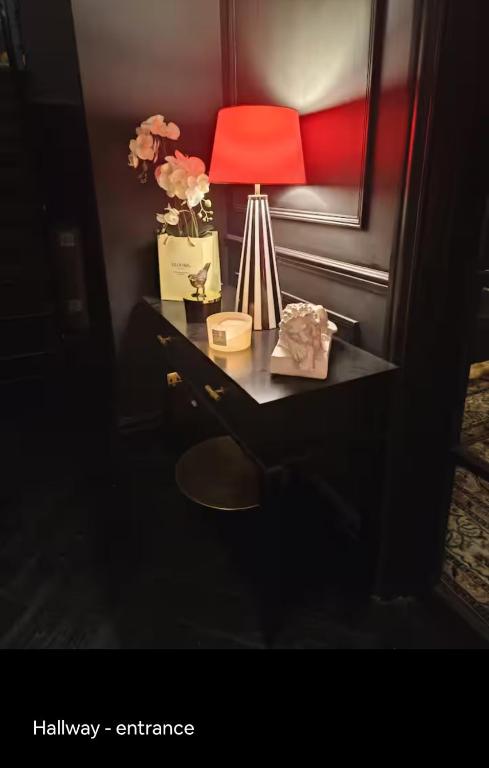 a desk with a red lamp and flowers on it at Room FULHAM TF2 in London