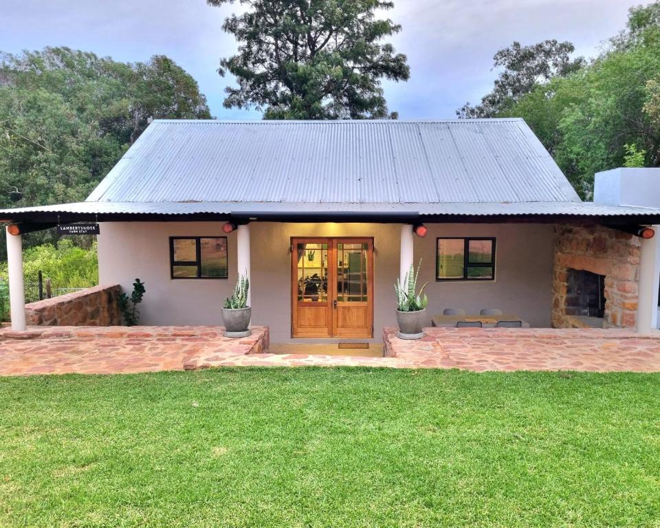 a small white house with a brown door at Lambertshoek Farm Stay in Clanwilliam