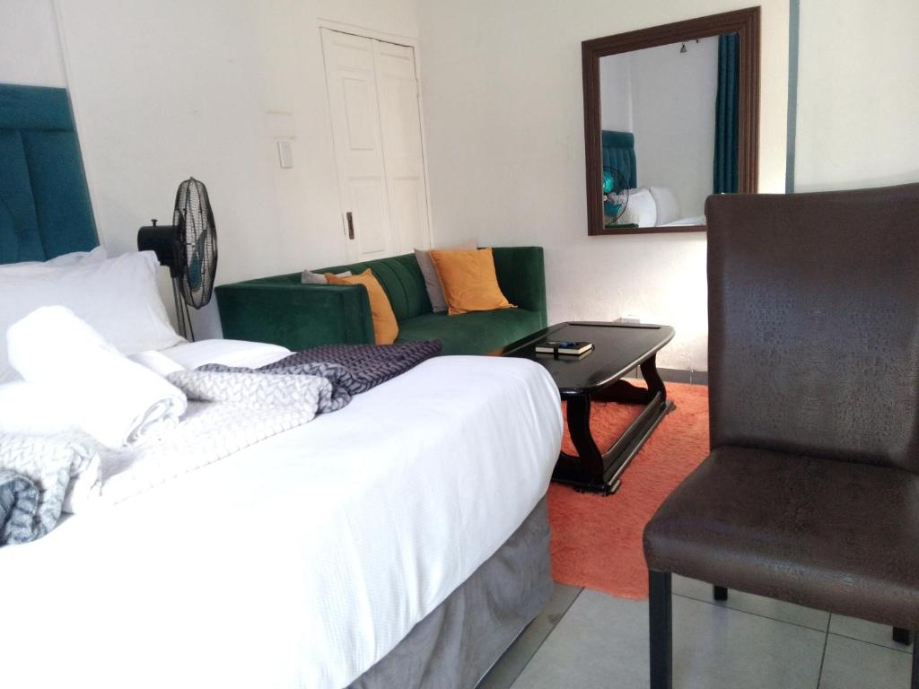 a bedroom with a bed and a couch and a chair at Lancaster Guest House in Boksburg