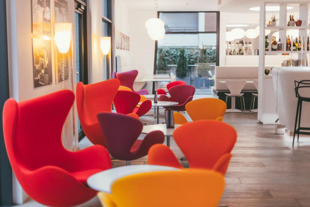 a row of red and orange chairs in a restaurant at Hotel City Lugano in Lugano