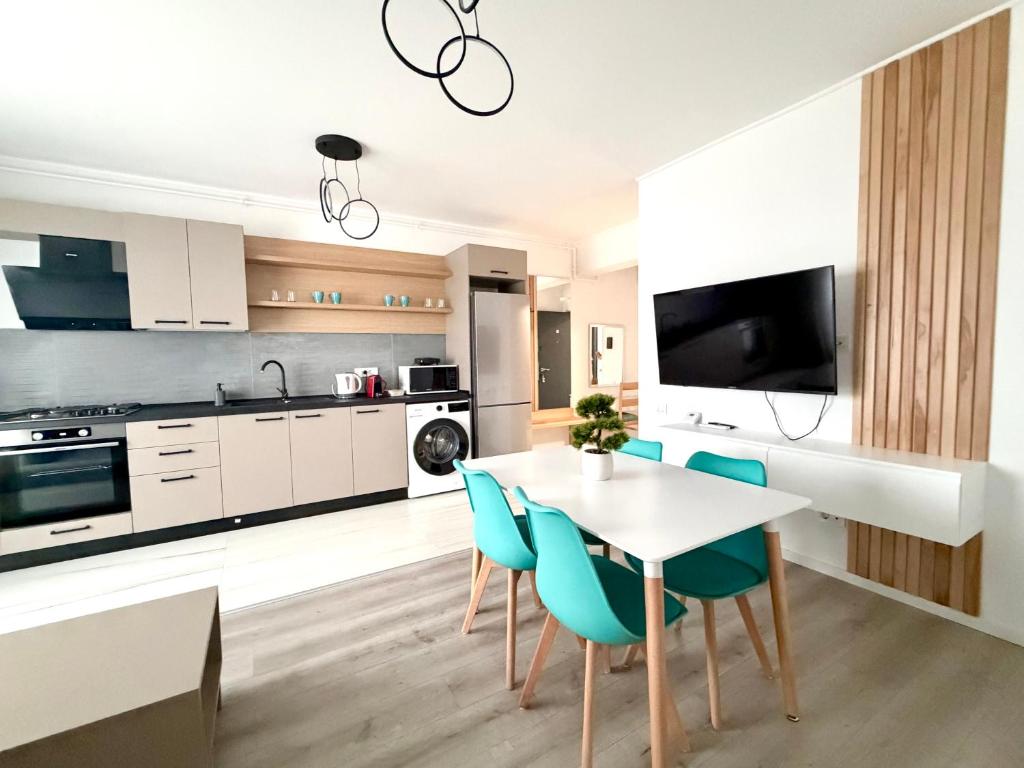 a kitchen with a white table and blue chairs at DOCA Apartments 10 in Otopeni