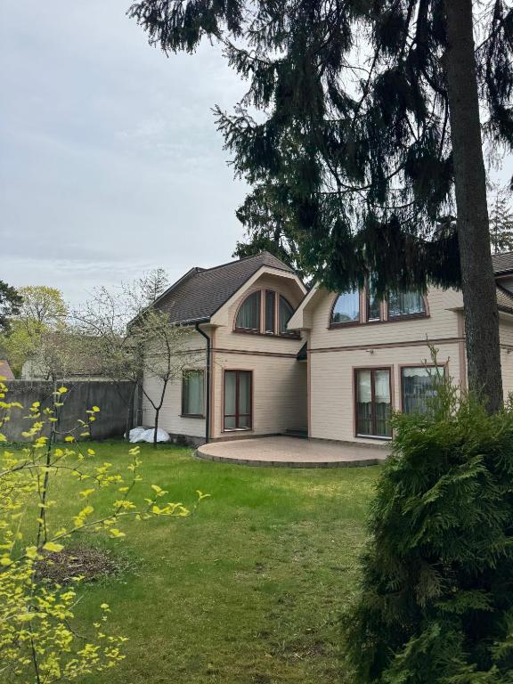 a white house with a tree in a yard at Saules home Jomas - early check in, late check out in Jūrmala