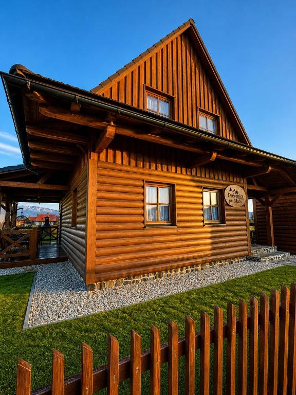 a wooden house with a fence in front of it at Tatralake Log Cabin - Drevenica pri Mare in Liptovský Mikuláš