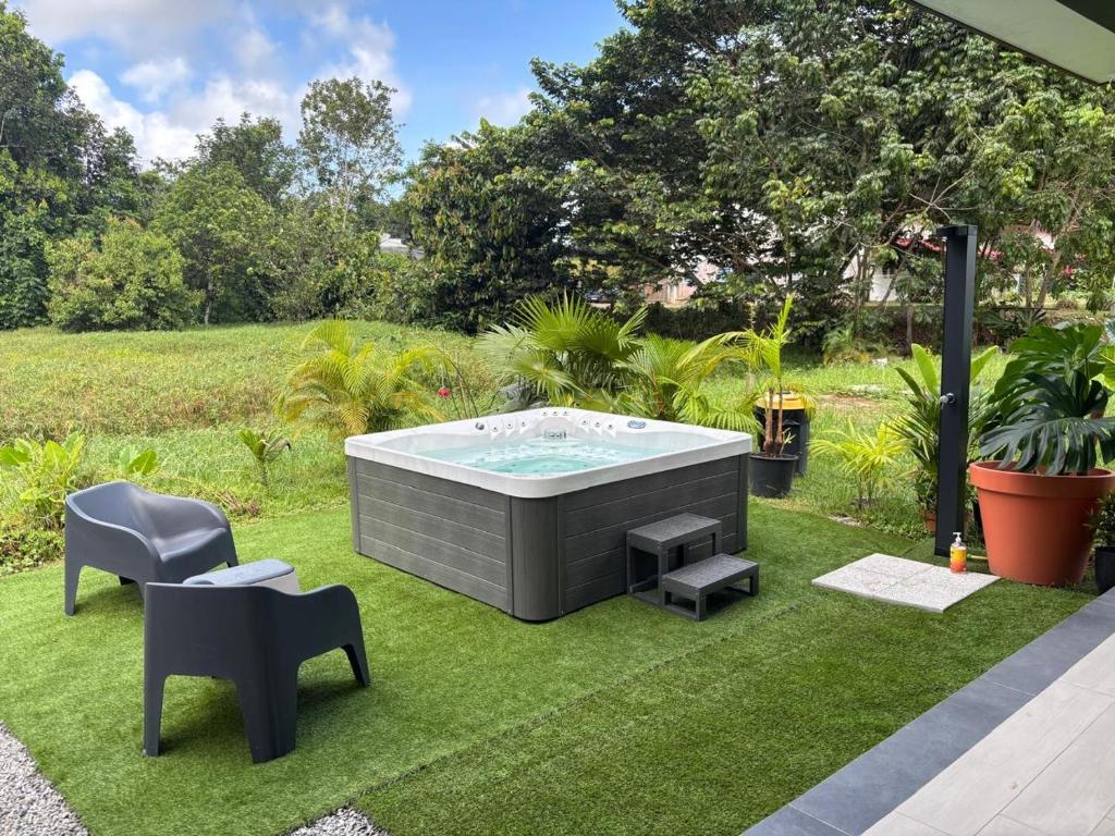 a garden with a hot tub on the grass at Tycoon Luxury, SPA Privatif, Lit XXL, Cinema in Matoury