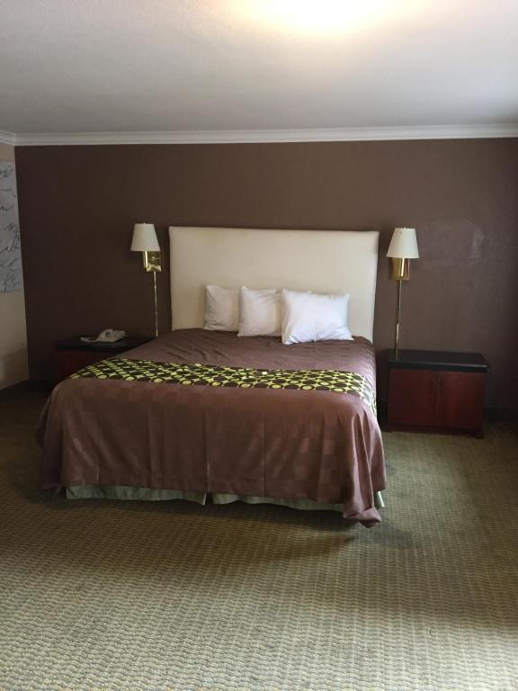 - un grand lit dans une chambre d'hôtel avec 2 lampes dans l'établissement American Inn Stockton, à Stockton