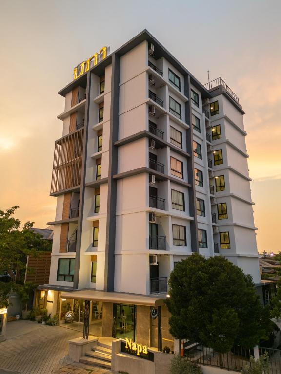 a tall white building with a hotel sign on it at Napa Hotel Ratchaburi in Ratchaburi