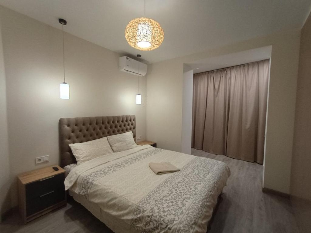 a bedroom with a large bed and a chandelier at Воскресенская 12 Евро in Dnipro