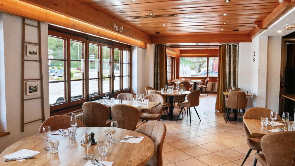 a restaurant with tables and chairs and windows at L'Echo des Montagnes Armoy in Armoy