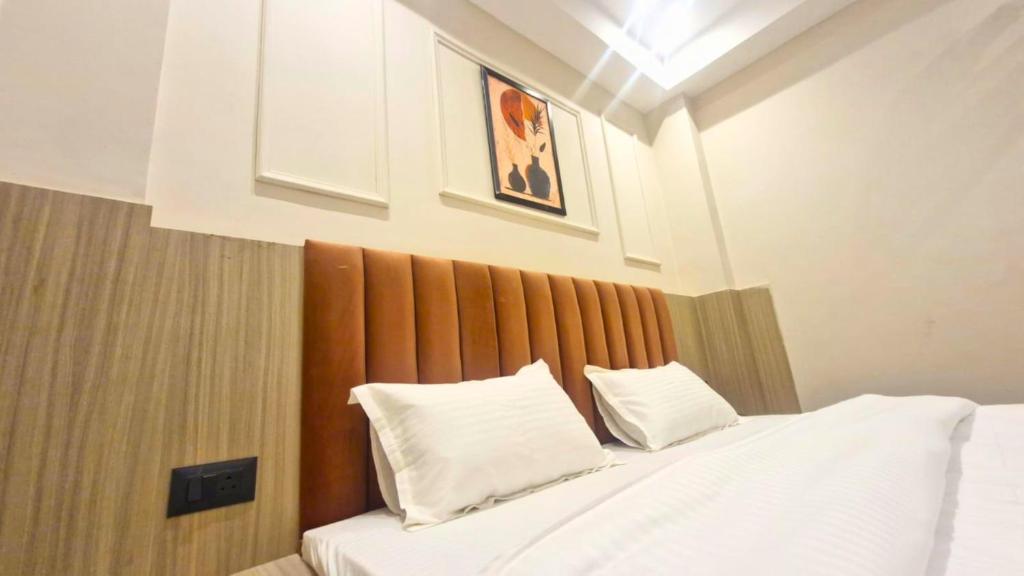 a bedroom with a bed with two white pillows at The City Hotel in Kānpur