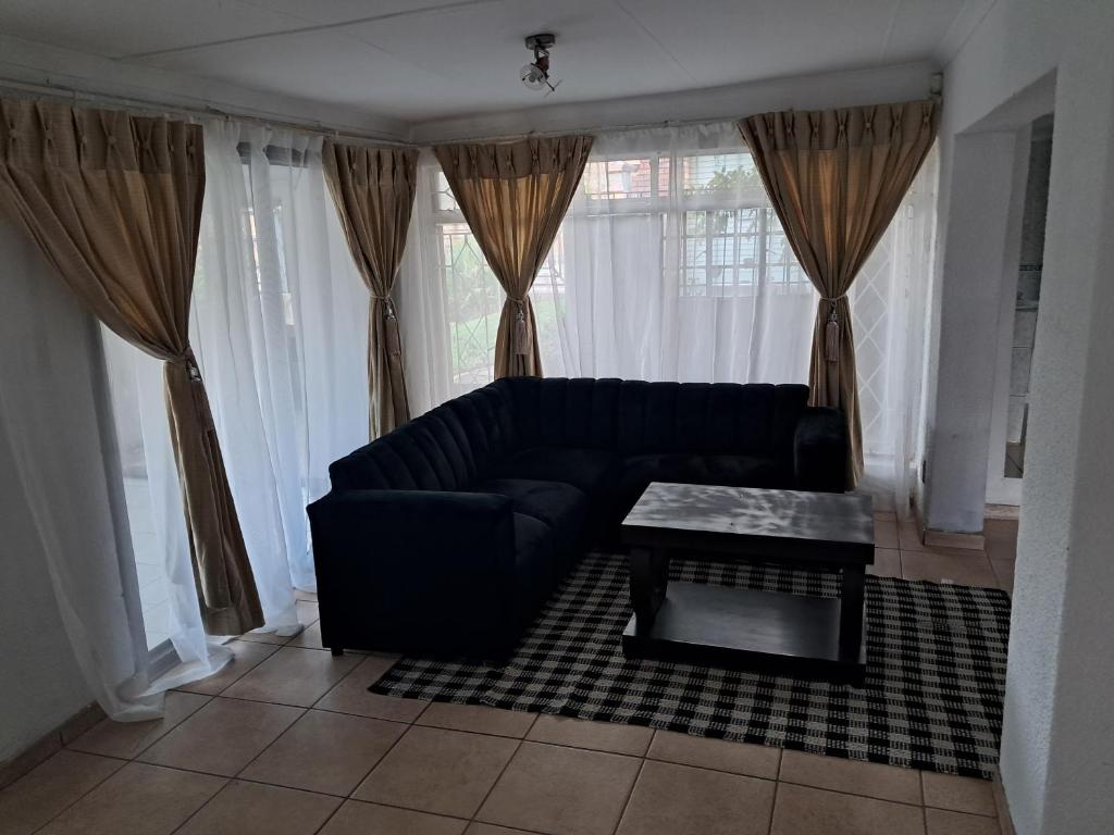 a living room with a black couch and a table at Charles Guest House in Germiston