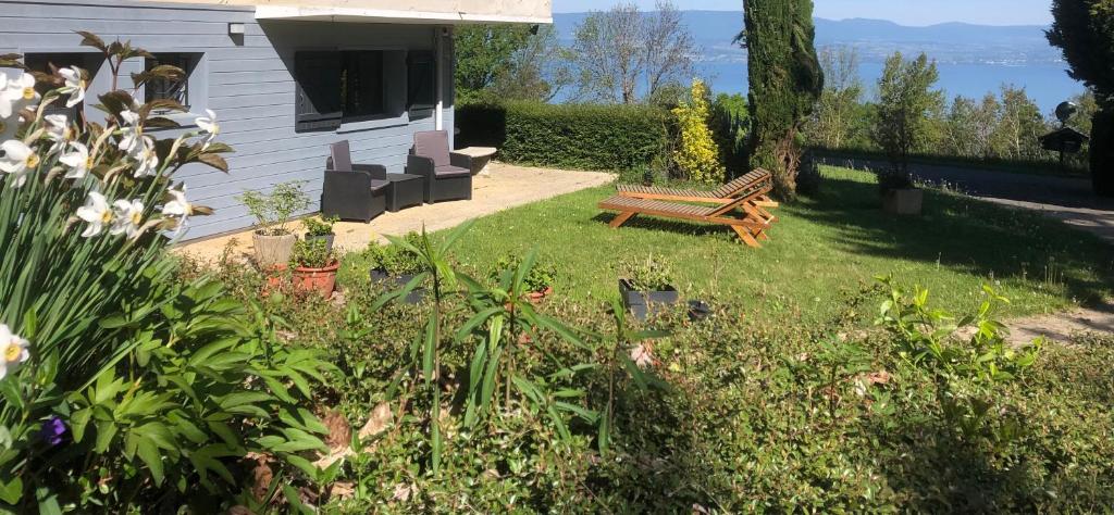 a garden with a bench and flowers and a house at Vue Lacustre in Publier