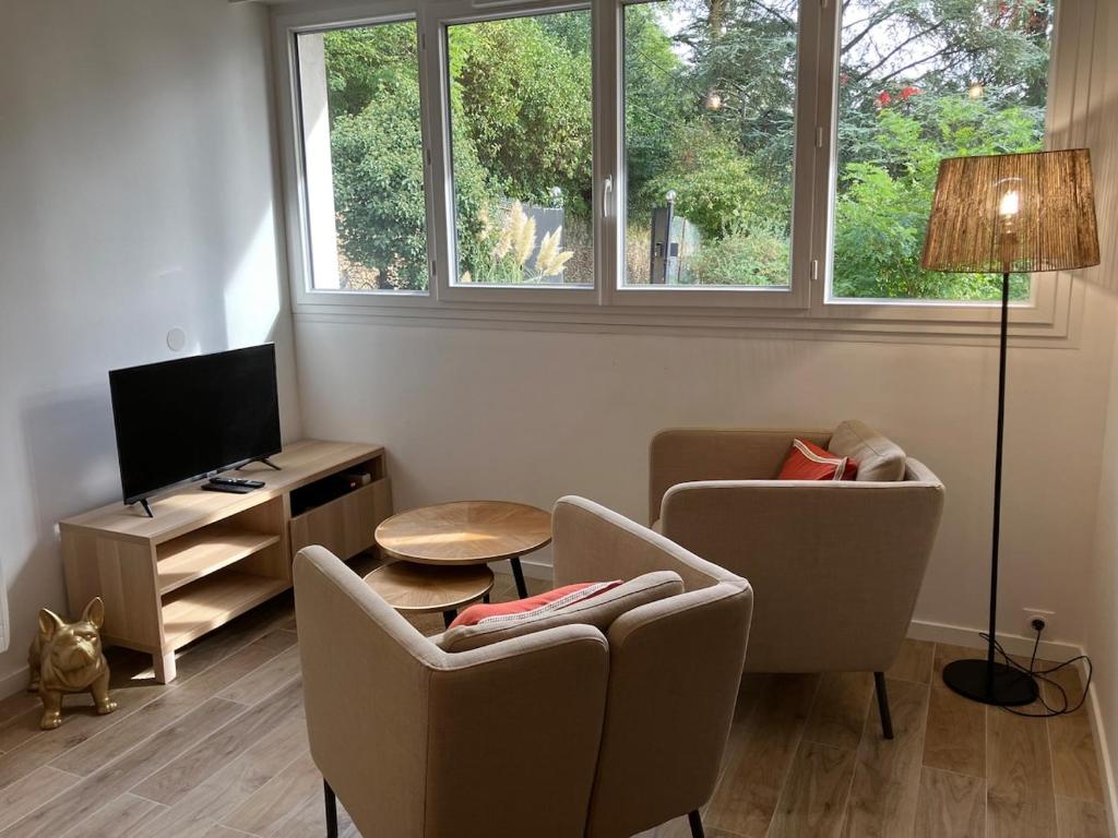 a living room with two chairs and a television at Studio Cosy près de la forêt in Saint-Prix