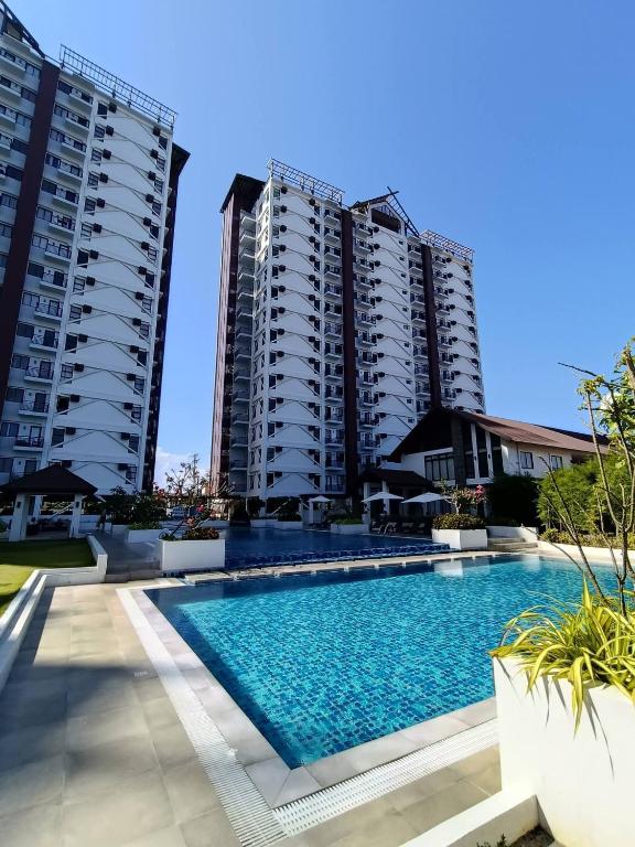 a swimming pool in front of two tall buildings at City View Studio Pool - Gym - Caesar Residence in Mactan Island