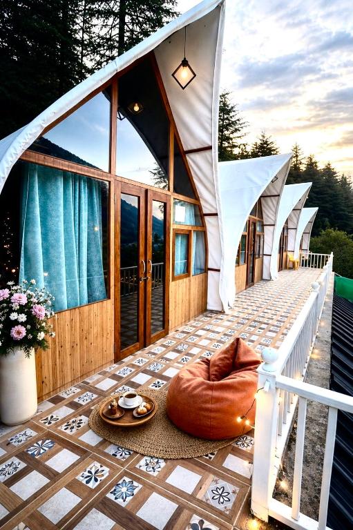 a house on a deck with a bean bag on the porch at Peakaboo Manali in Manāli