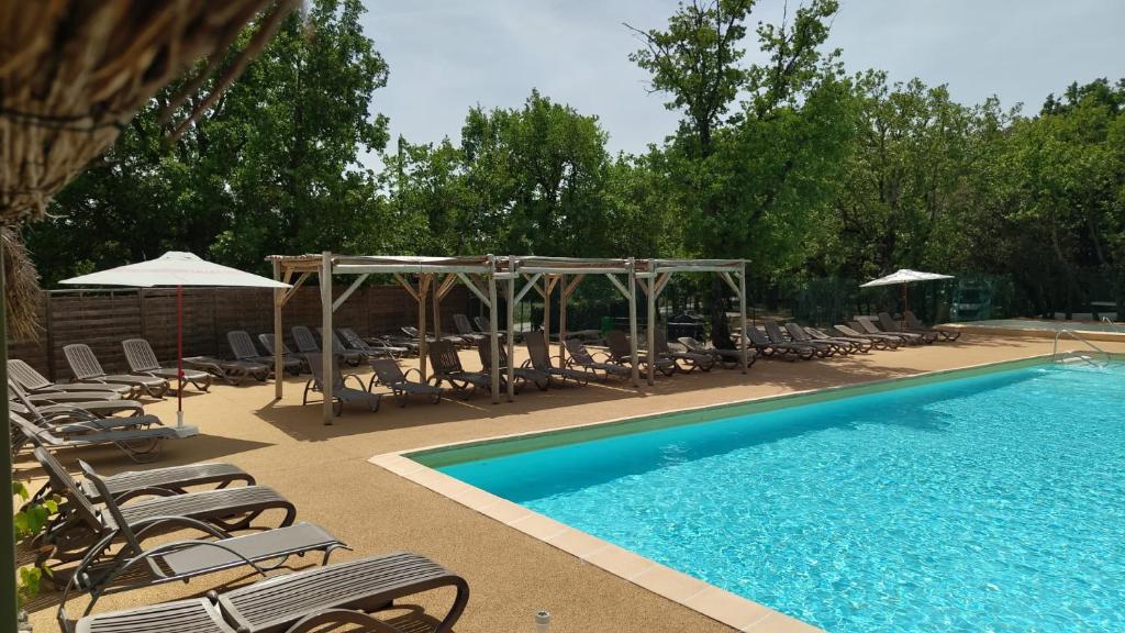 a swimming pool with chairs and umbrellas at Domaine Les Chênes Blancs in Saint-Saturnin-lès-Apt