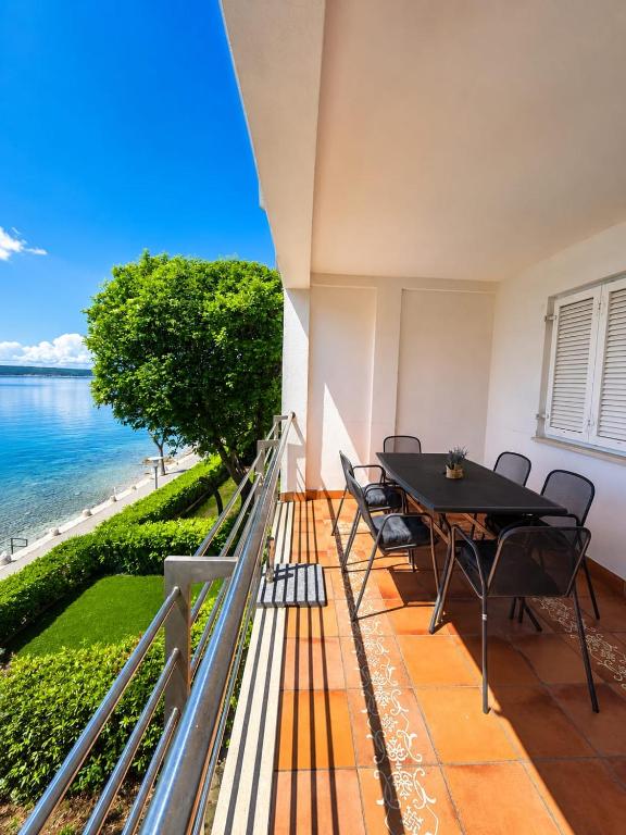 a balcony with a table and chairs and the ocean at App LOLLY in Selce