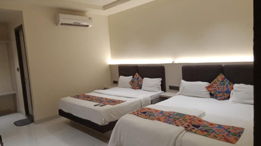 two beds in a room with white walls at Hotel Santoor - Geeta Bhawan Square in Indore