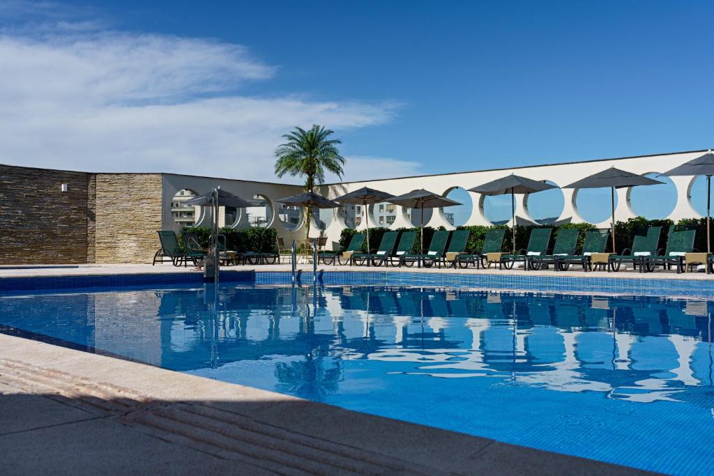 a large swimming pool with chairs and umbrellas at Bourbon Convention Hotel Santos in Santos